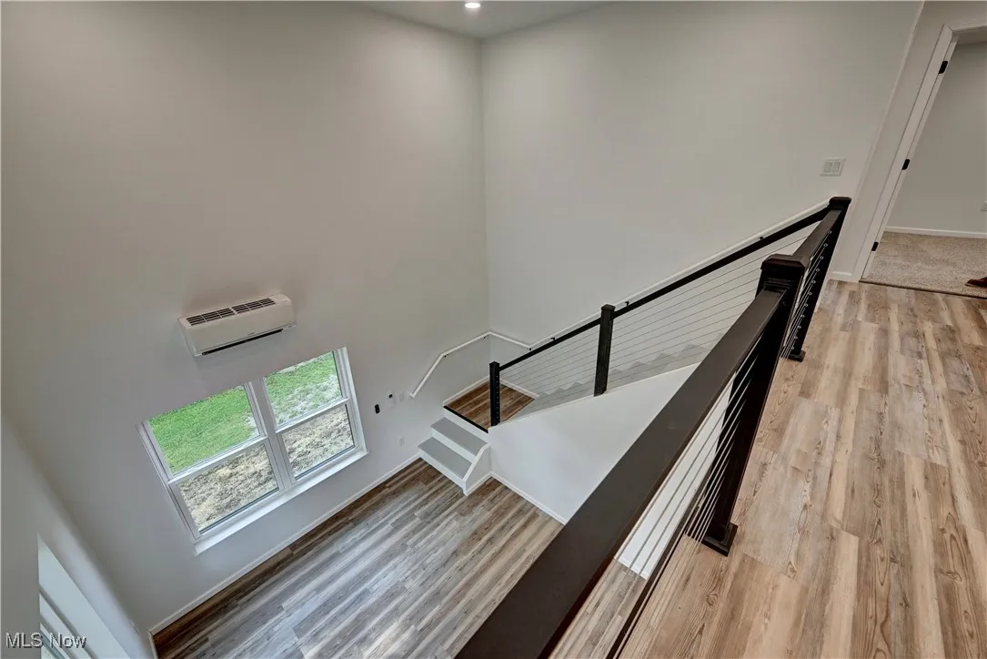 Stairs with wood finished floors, a towering ceiling, and recessed lighting