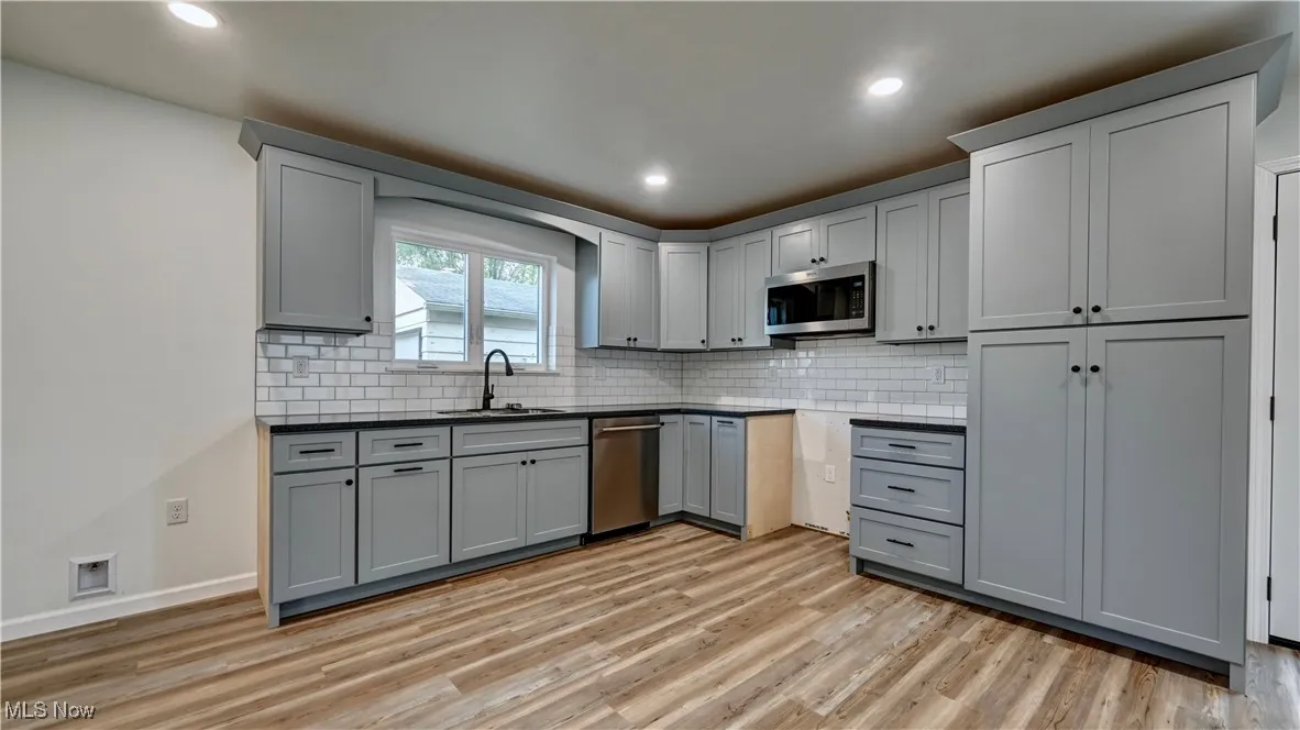 Kitchen featuring gray cabinetry, decorative backsplash, light wood finished floors, and recessed lighting