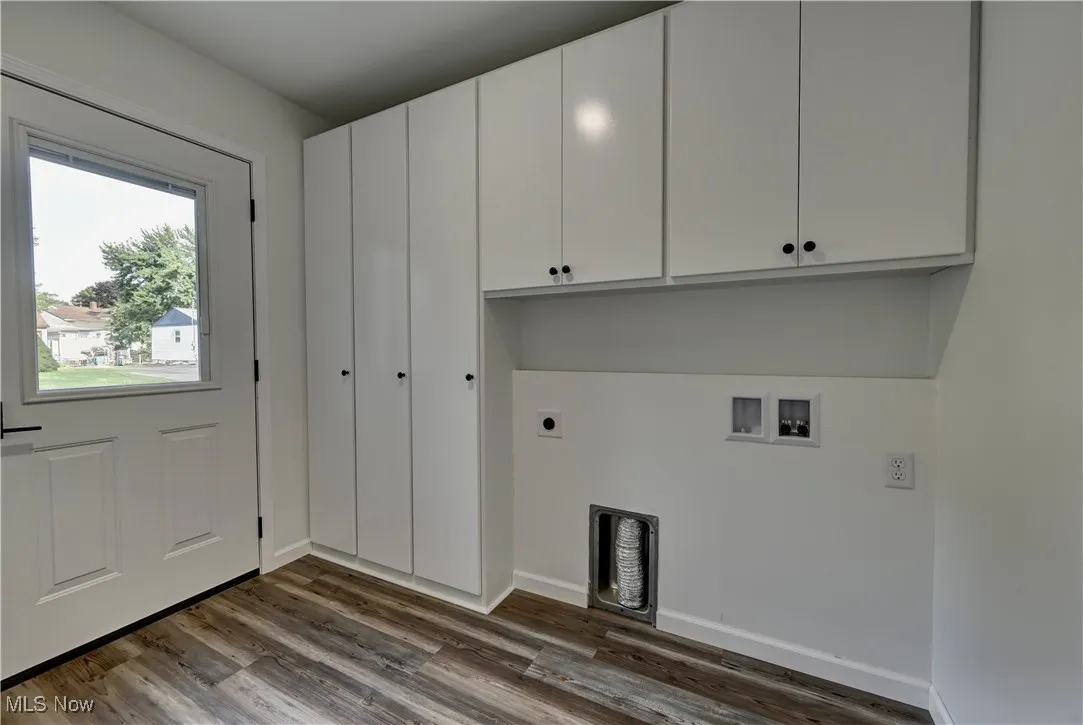 Laundry area featuring electric dryer hookup, hookup for a washing machine, cabinet space, and dark wood-style flooring