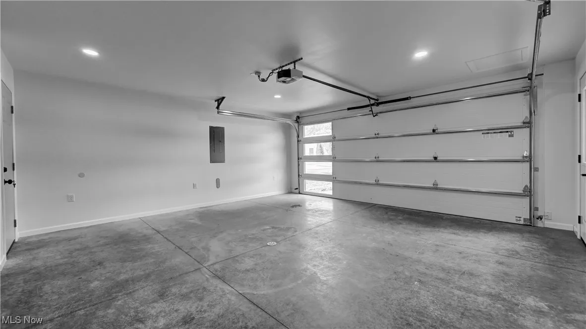 Garage featuring electric panel, recessed lighting, and a garage door opener
