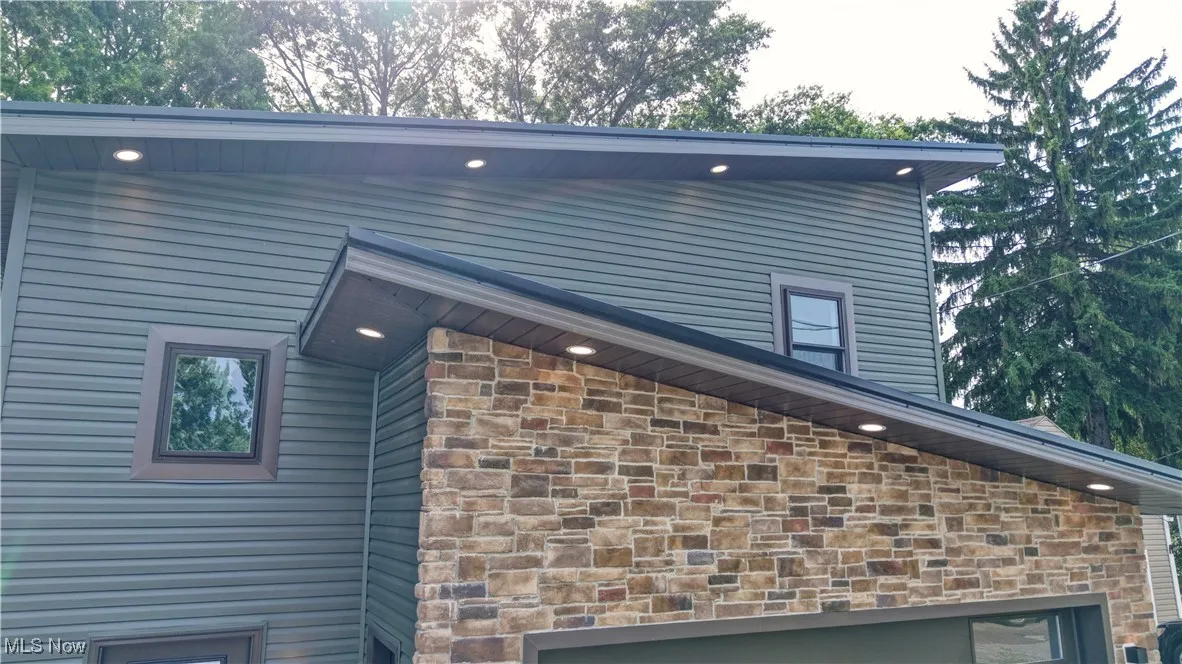 View of side of property with stone siding and a garage