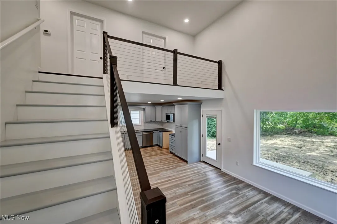 Stairway featuring recessed lighting, wood finished floors, and a towering ceiling