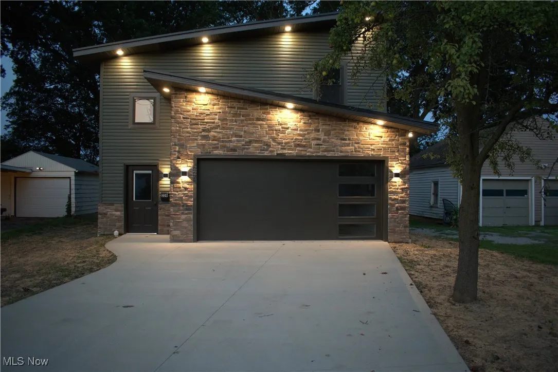 View of front of property with stone siding, concrete driveway, and an outdoor structure