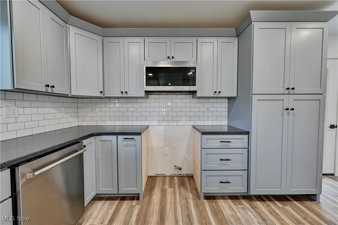 Kitchen with appliances with stainless steel finishes, light wood-type flooring, and tasteful backsplash
