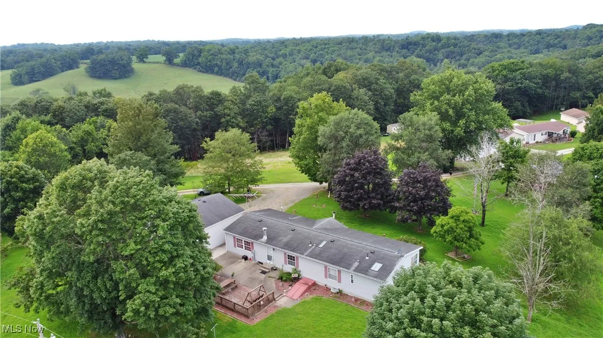 Aerial view of property and surrounding area with a heavily wooded area