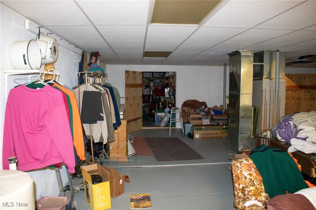 Finished below grade area with a drop ceiling, heating unit, and concrete block wall