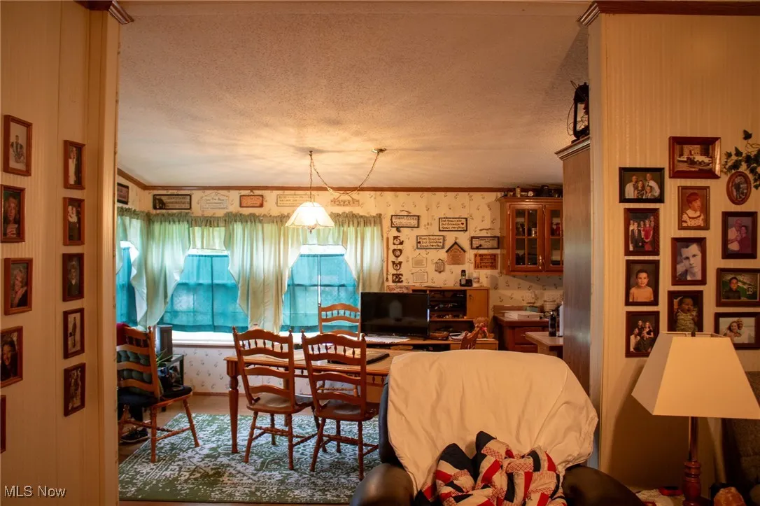Living room with wallpapered walls and a textured ceiling