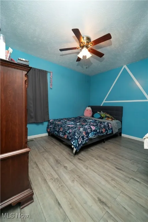 Bedroom featuring wood finished floors, a textured ceiling, and ceiling fan
