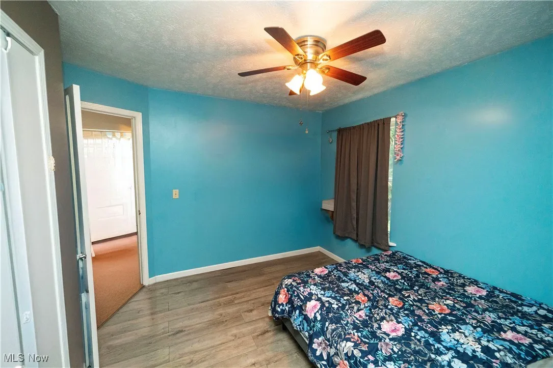 Bedroom featuring a textured ceiling, wood finished floors, and ceiling fan
