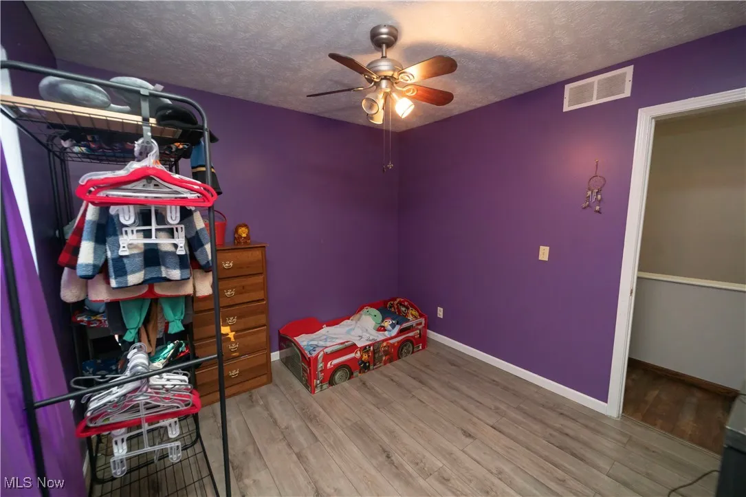 Bedroom featuring a textured ceiling, wood finished floors, and a ceiling fan