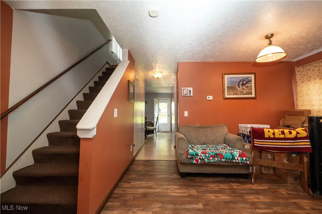 Living area with wood finished floors, a textured ceiling, and stairs