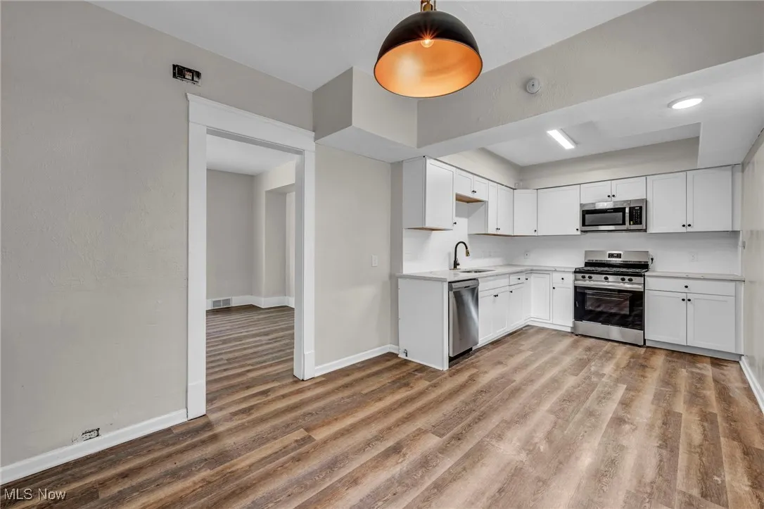 Kitchen featuring decorative backsplash, wood finished flooring, brand new cabinets and quartz countertops and pendant lighting