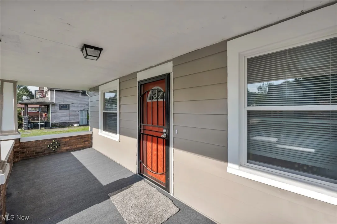 View of covered front porch and vibrant orange front door