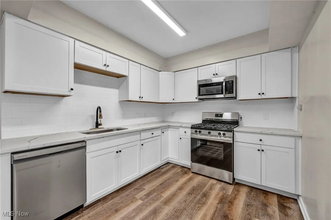 Kitchen featuring stainless steel appliances, white cabinetry, wood finished