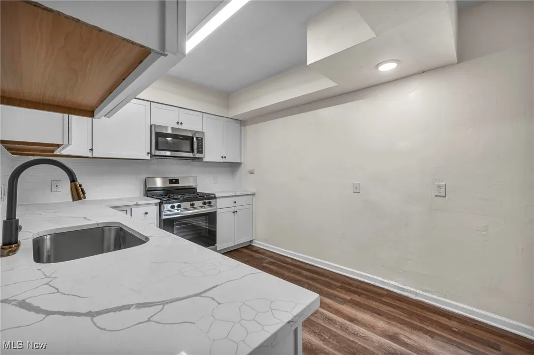 Kitchen featuring decorative backsplash, wood finished flooring, brand new cabinets and quartz countertops