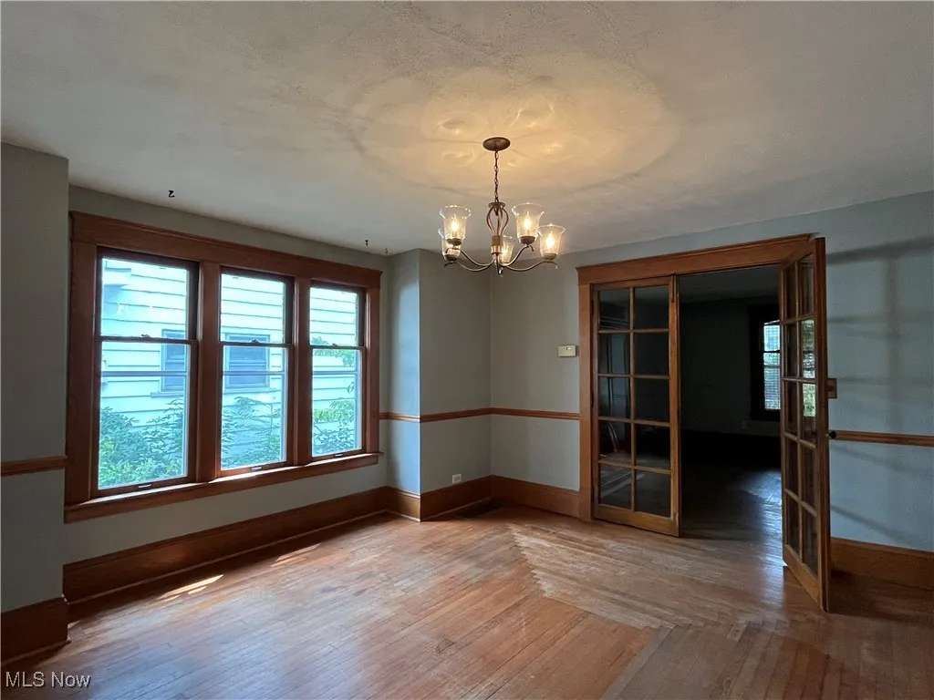Unfurnished dining area with wood-type flooring and a chandelier