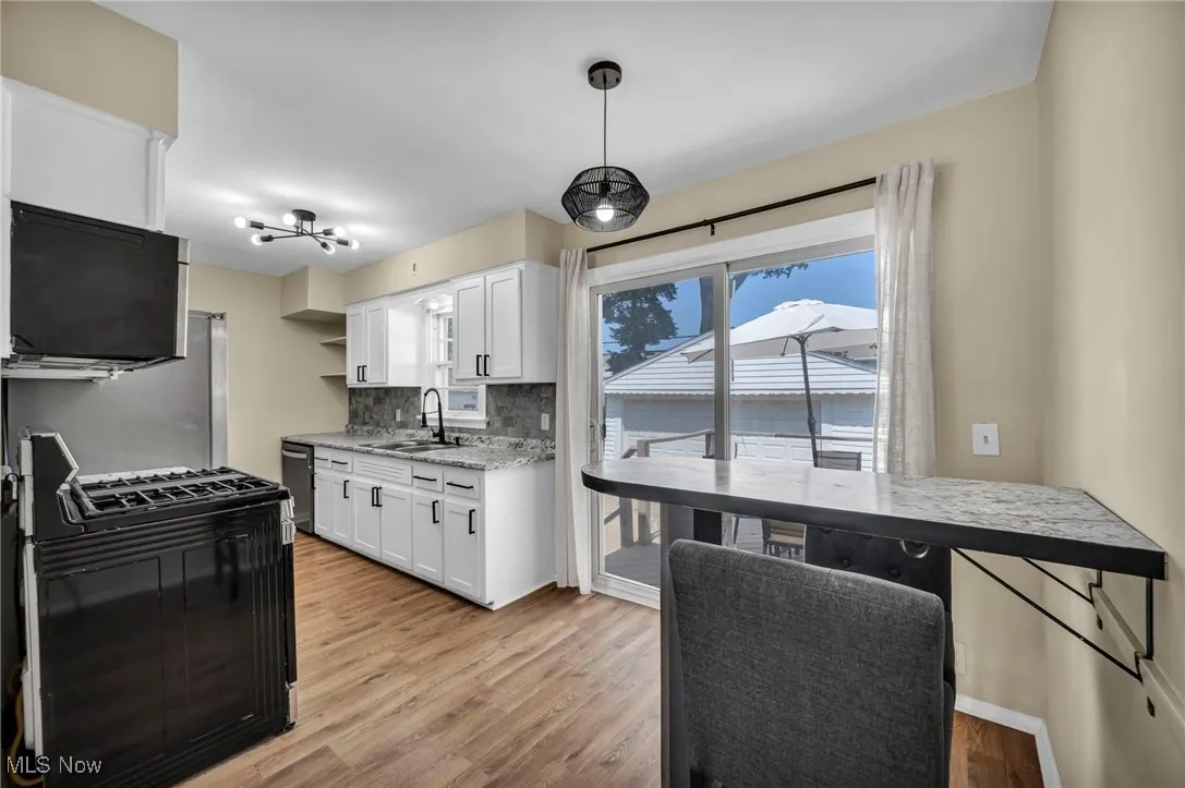 Kitchen featuring range with gas cooktop, tasteful backsplash, light wood-style floors, white cabinets, and open shelves