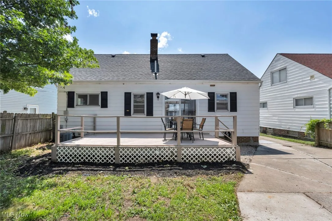 Back of property with roof with shingles, a deck, and a chimney