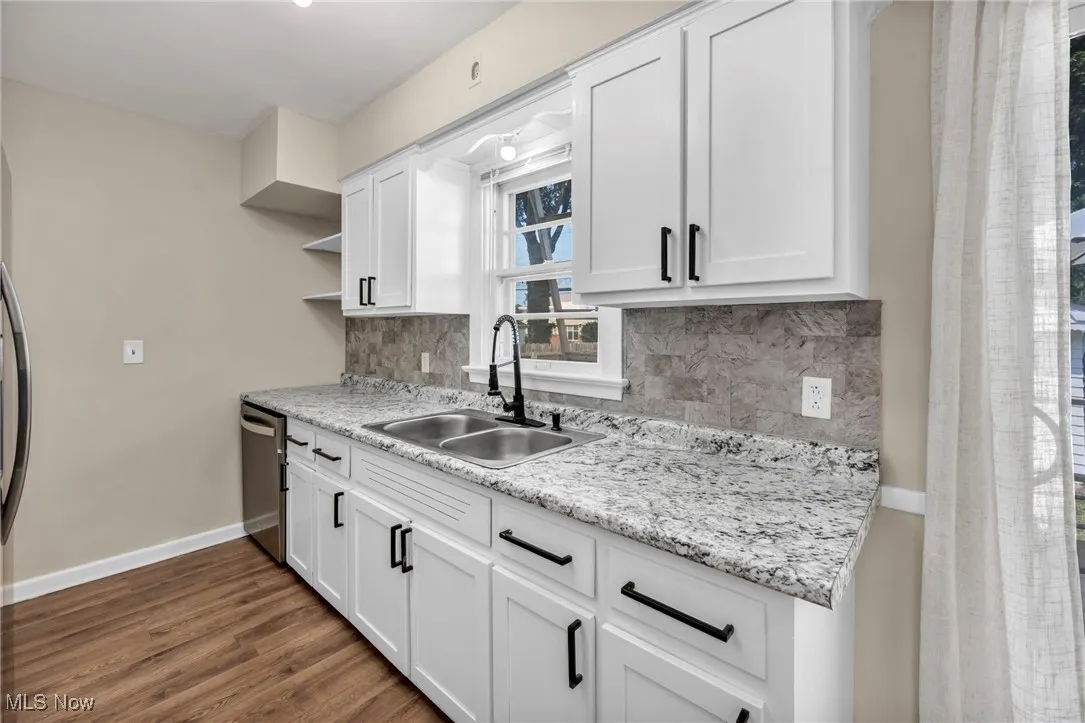 Kitchen with backsplash, open shelves, white cabinetry, dark wood finished floors, and stainless steel dishwasher