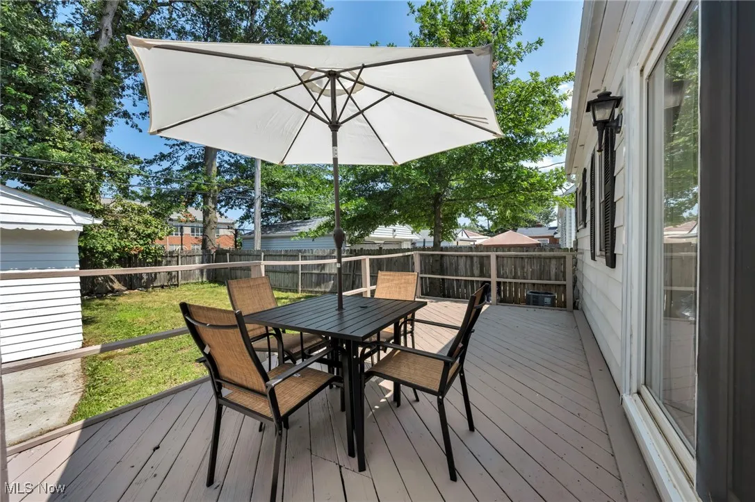 Wooden deck with outdoor dining space and a fenced backyard