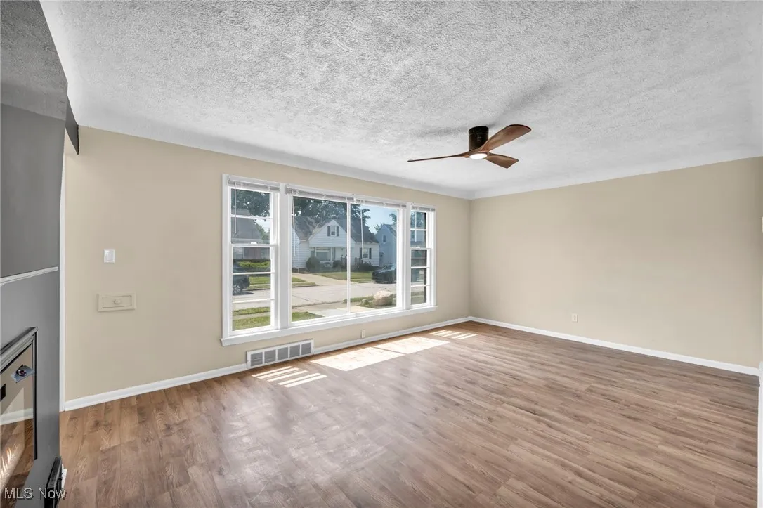 living room featuring wood finished floors, a ceiling fan, and a textured ceiling