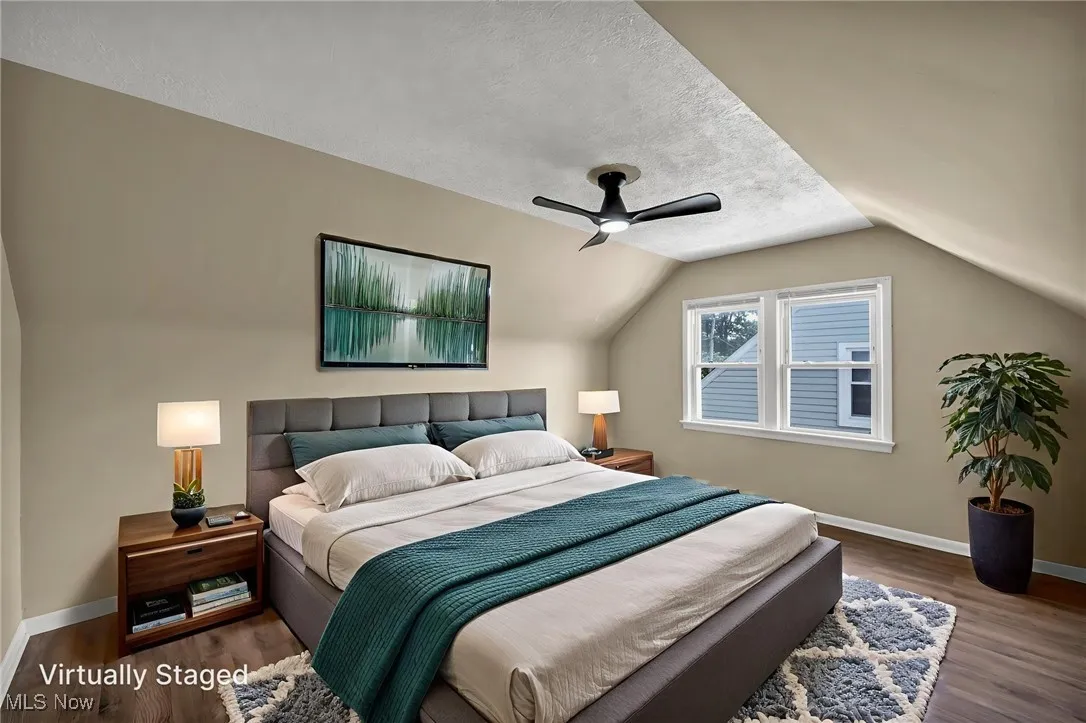 Bedroom with wood finished floors, a textured ceiling, vaulted ceiling, and ceiling fan