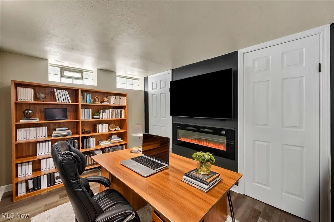 Office space featuring a textured ceiling, a glass covered fireplace, and dark wood-style flooring
