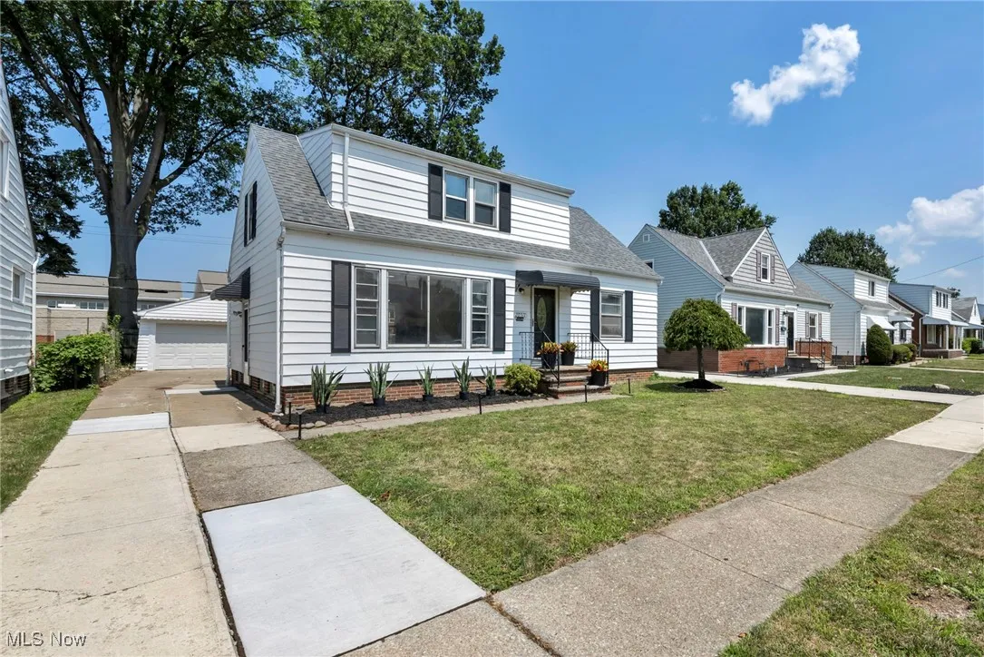 Bungalow with a shingled roof, an outbuilding, a front lawn, and a garage