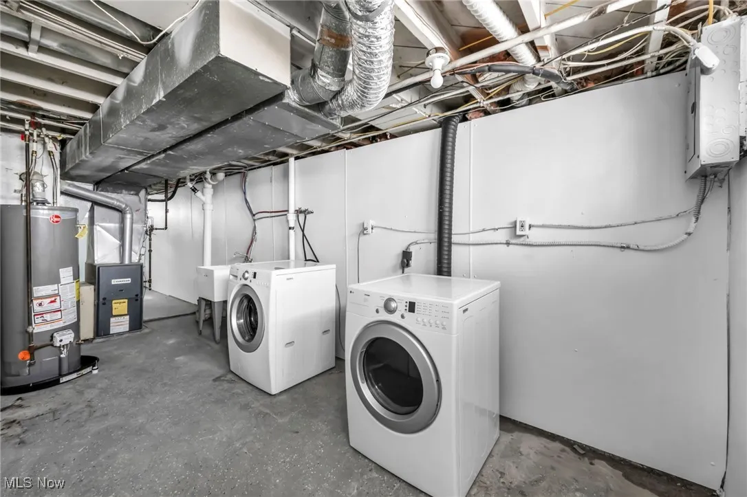 Laundry room with washing machine and dryer, gas water heater, electric panel, and heating unit