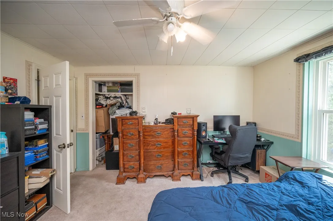 Bedroom with light colored carpet, an office area, a ceiling fan, and a closet