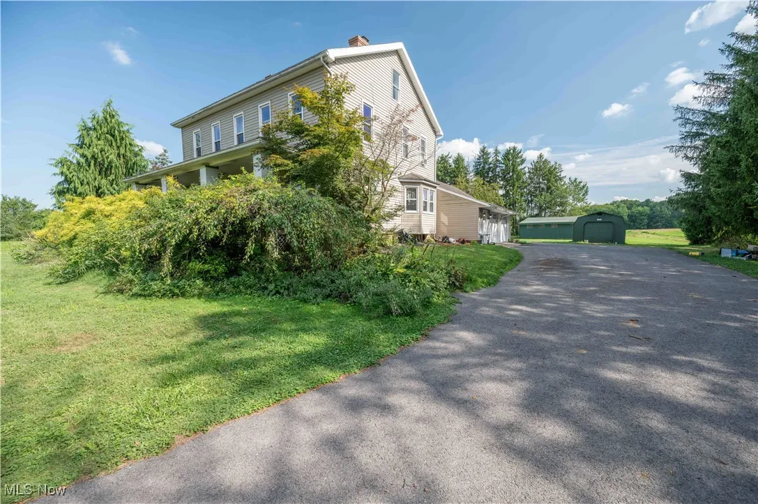View of side of home featuring an outdoor structure, a yard, a chimney, and a detached garage