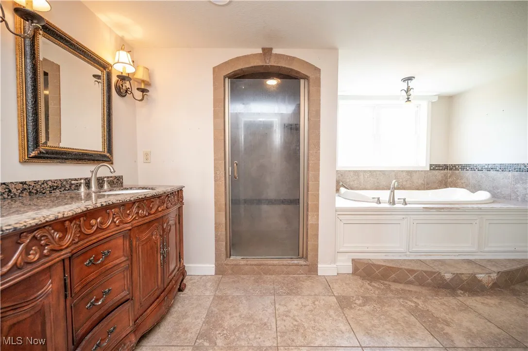 Full bathroom with a garden tub, vanity, a shower stall, and tile patterned floors