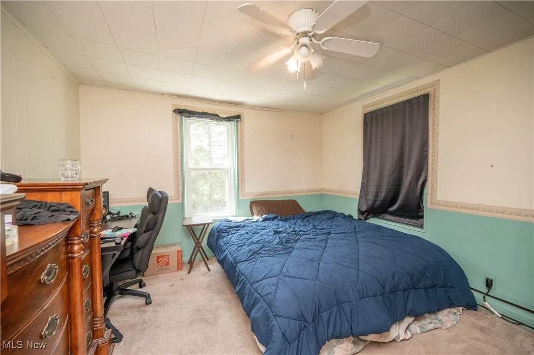 Bedroom featuring carpet floors, an office area, wainscoting, and a ceiling fan