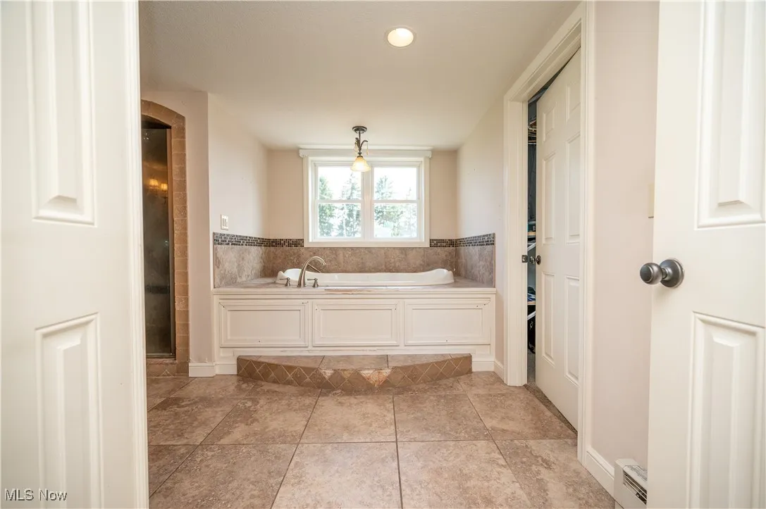 Bathroom with a bath, a baseboard radiator, tile patterned floors, and a shower with shower door