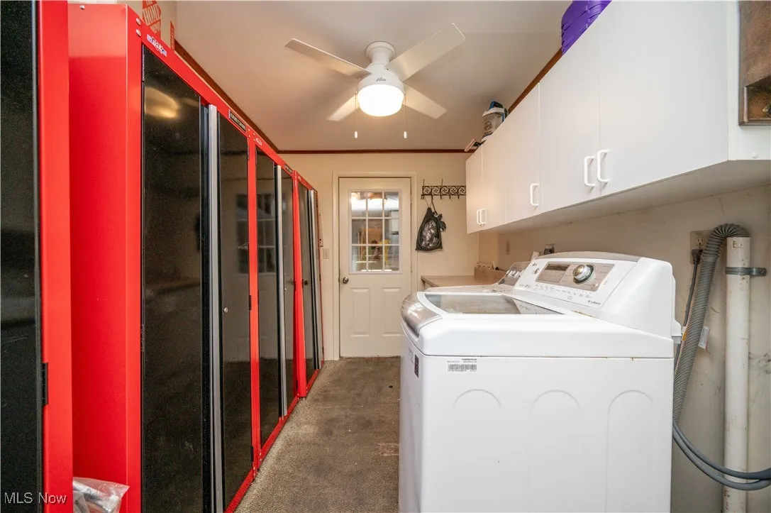 Laundry area featuring cabinet space, washer and dryer, ornamental molding, a ceiling fan, and carpet floors
