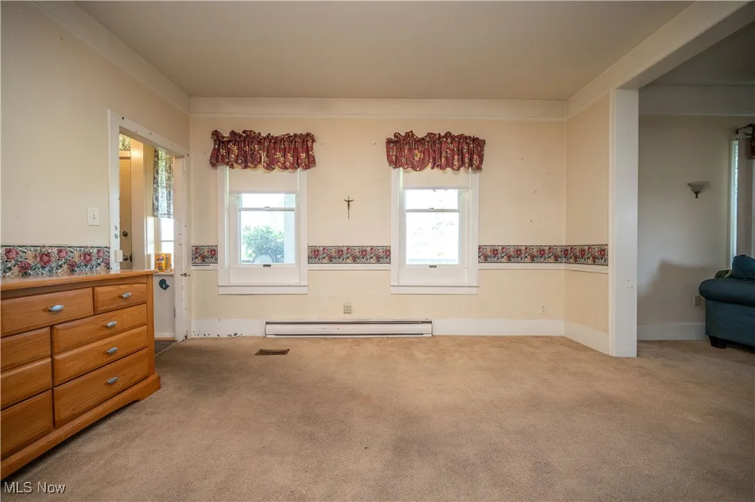 Carpeted empty room featuring a baseboard radiator and baseboards