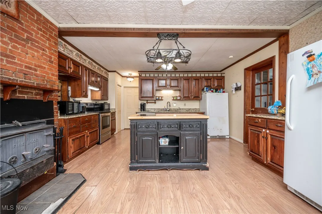 Kitchen with an ornate ceiling, light countertops, crown molding, freestanding refrigerator, and light wood-type flooring