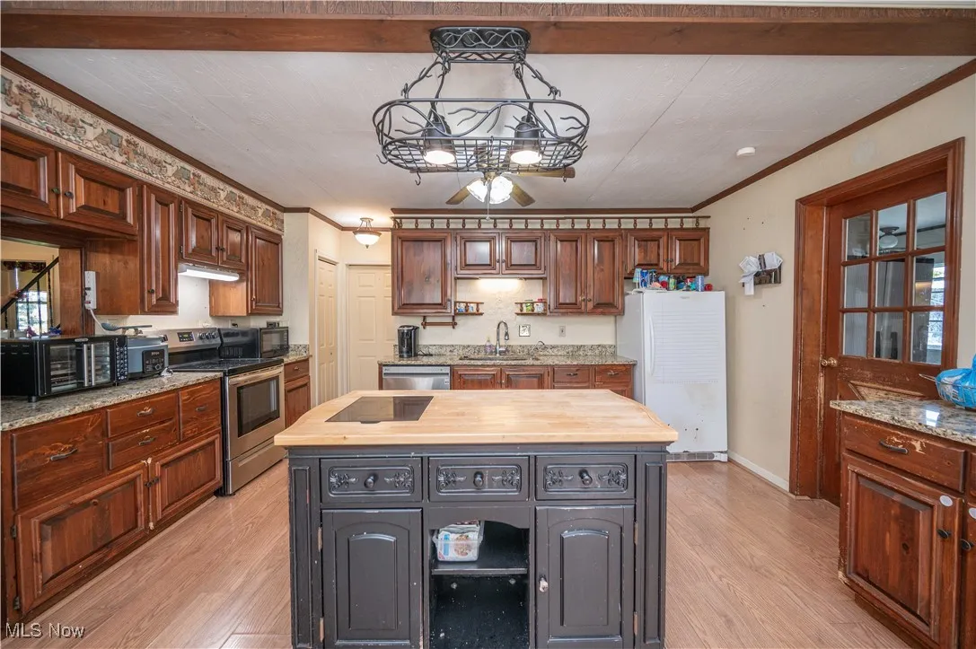 Kitchen with light wood-style floors, black appliances, wooden counters, crown molding, and a chandelier