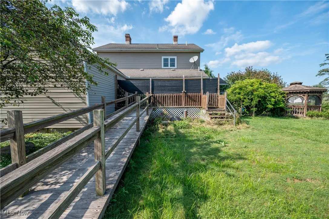Back of property with a chimney, a yard, and a wooden deck
