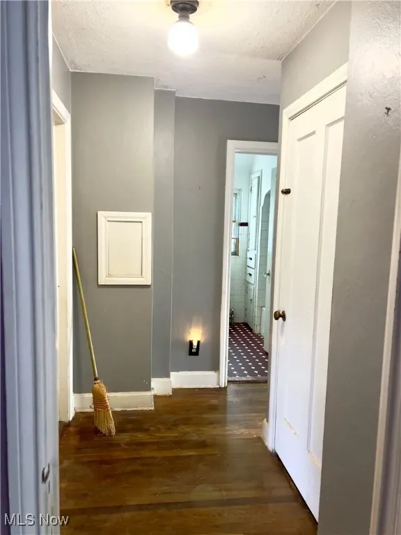 Hallway with wood finished floors and a textured ceiling