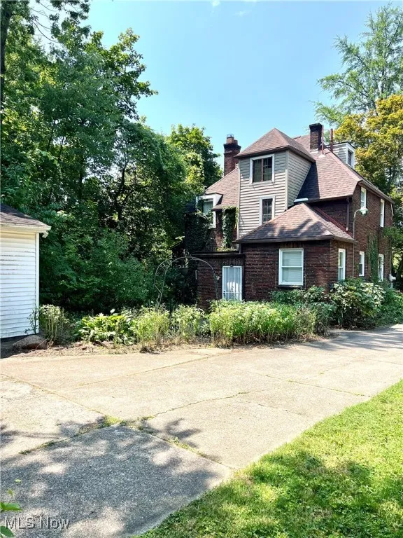 View of side of home featuring a chimney and brick siding