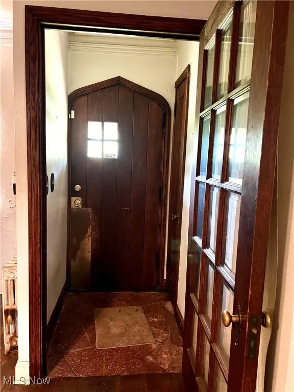Entryway featuring ornamental molding, radiator heating unit, and arched walkways