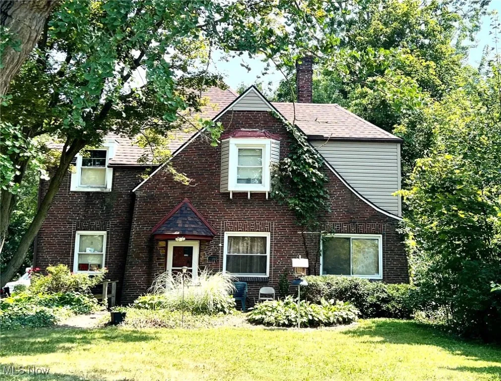 Tudor home with a chimney, a front yard, and brick siding