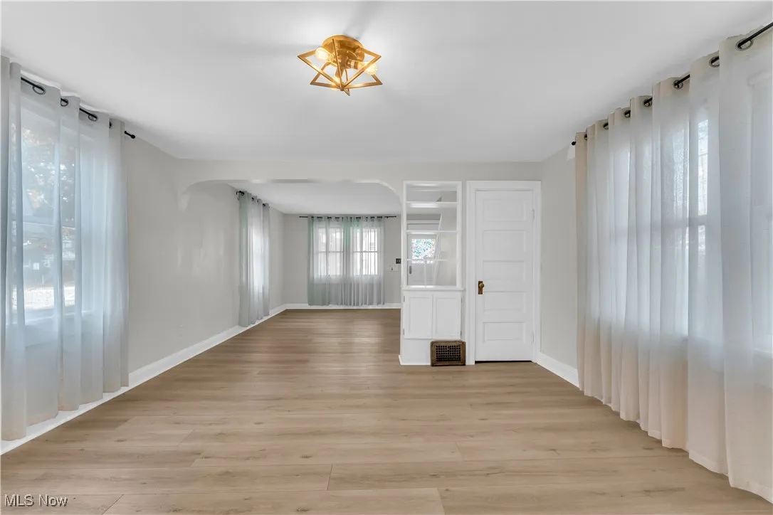 Empty room with light wood-style floors and arched walkways
