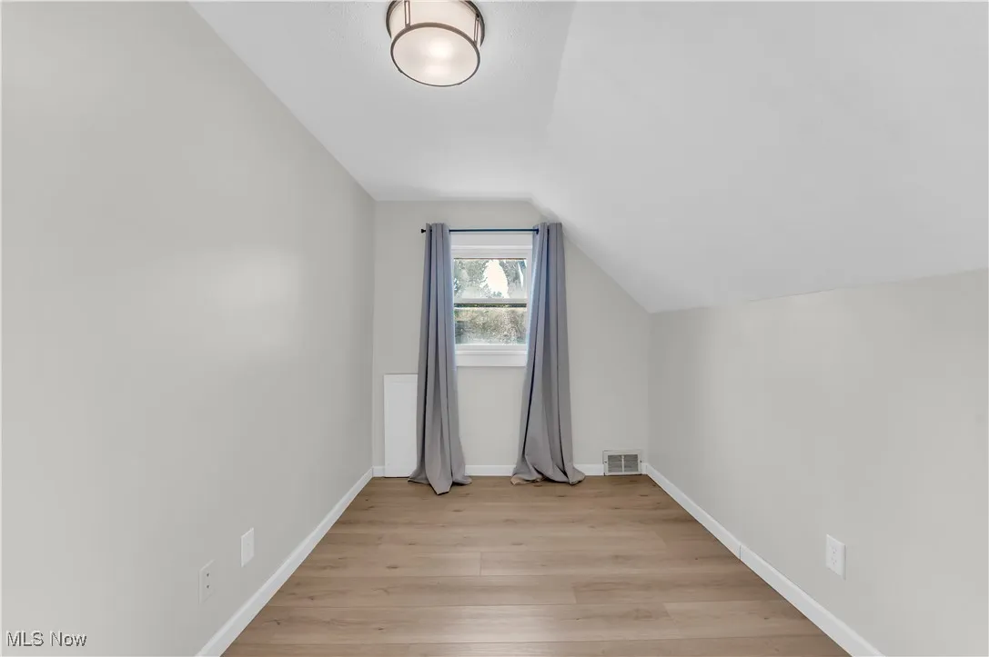 Bonus room featuring light wood-style floors and lofted ceiling