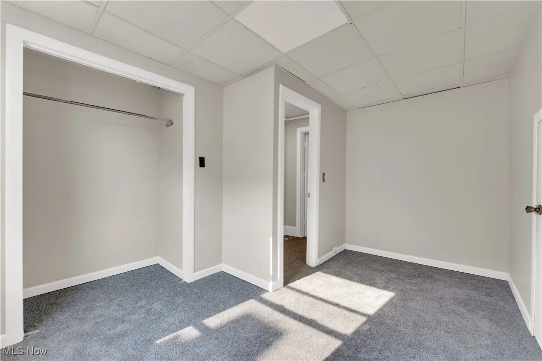 Unfurnished bedroom with carpet flooring and a drop ceiling
