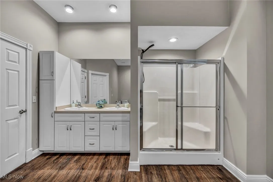 Bathroom with a stall shower, wood finished floors, and double vanity