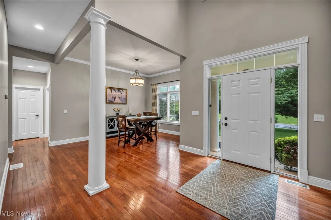 Entrance foyer with wood-type flooring, ornate columns, a chandelier, crown molding, and recessed lighting