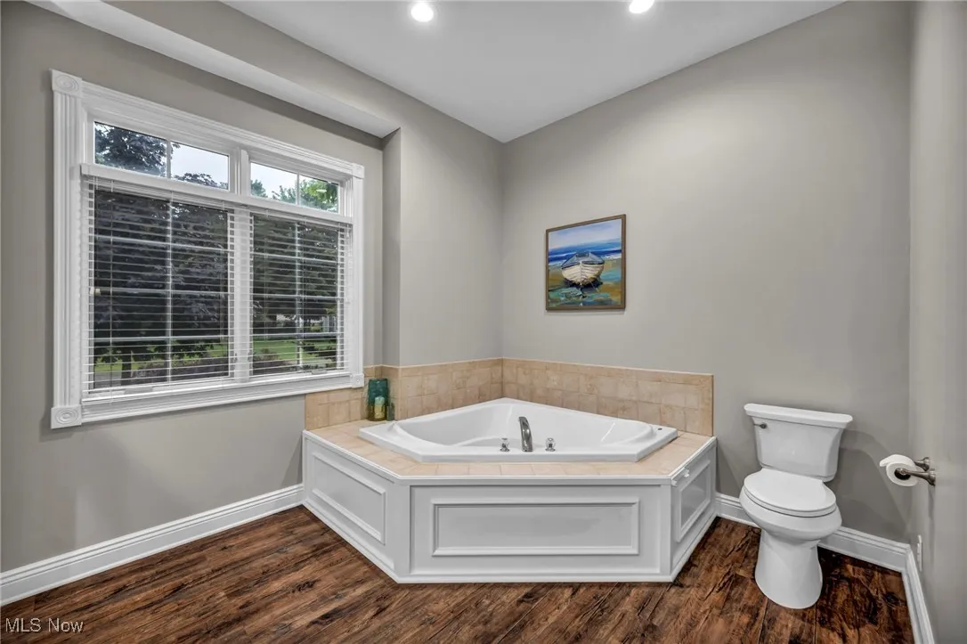 Bathroom with a bath, wood finished floors, and recessed lighting
