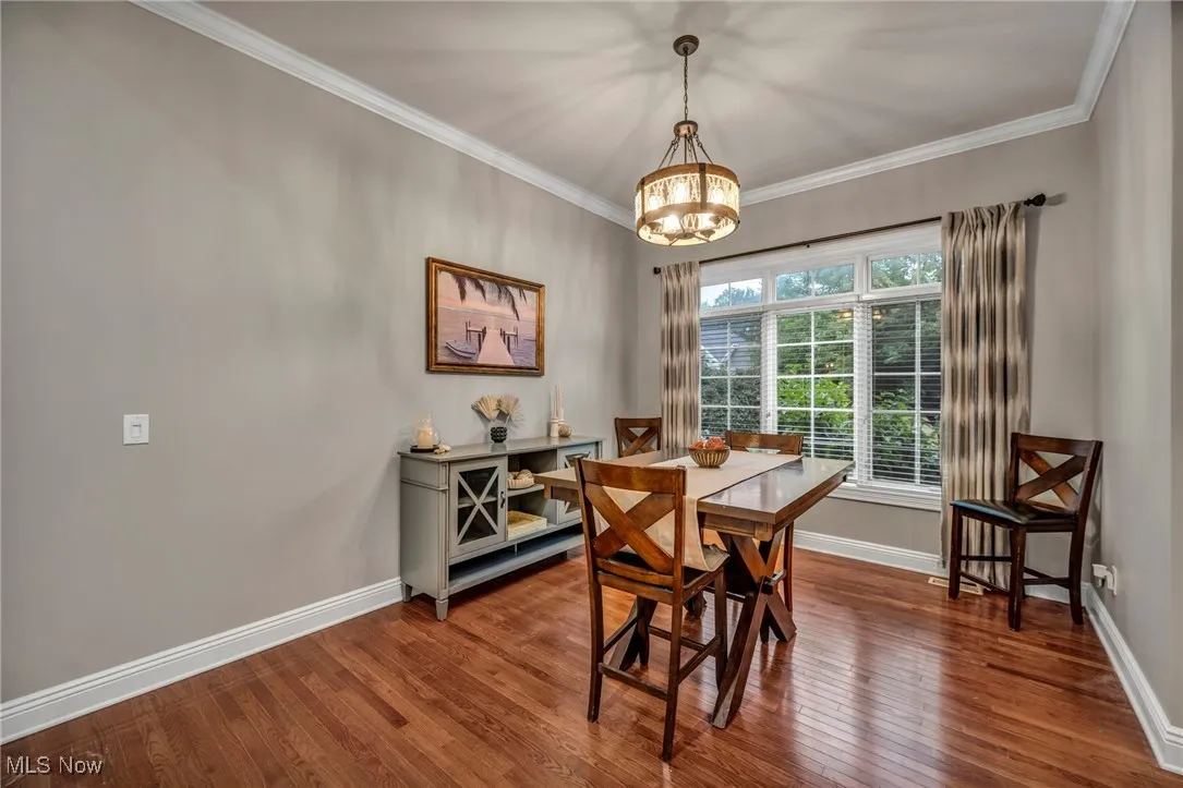Dining room featuring a chandelier, hardwood / wood-style floors, and crown molding